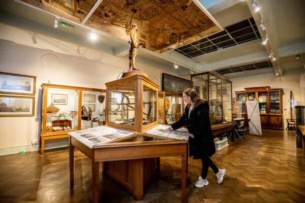 Girl looking at artefacts with statue of Captain Cook above